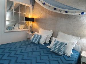 Schlafzimmer mit einem Bett mit blauen und weißen Kissen in der Unterkunft Dimitra's Sea-Crafts Boutique Studios in Kalyves