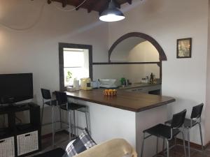 a kitchen with a counter with stools and a table at Casa Malbusca in Almagrinha