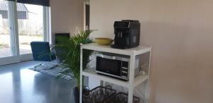 a microwave on a white stand with a tv and a microwave at Ermerhoek, in de Hof in Erm
