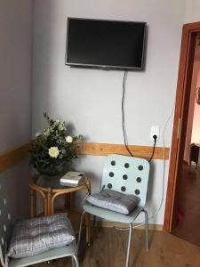 レバルにあるVilla Honoratkaの壁にテレビと椅子2脚が備わる客室です。
