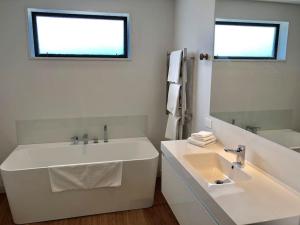 a white bathroom with a tub and a sink at The Yellow Door in Wanaka +18 photos
