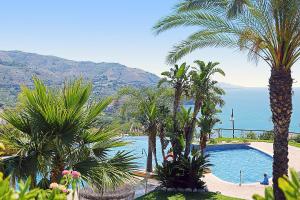 widok na basen z palmami i ocean w obiekcie Casa Indigo w Almuñécar