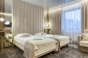 um quarto de hotel com duas camas e uma cadeira em Hotel & Spa Biały Dom em Gliwice