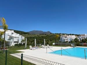 a swimming pool with lounge chairs next to a building at PALMSEA Marbella-Estepona in Buenas Noches
