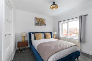 een slaapkamer met een blauw bed en een raam bij Modern Three Bedroom Gloucester Home in Gloucester