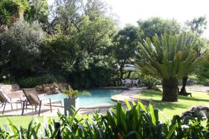 una piscina en un patio con sillas y árboles en Green Pascua, en Roodepoort