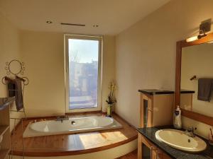 un bagno con vasca, 2 lavandini e finestra di Huize La Passion vacationhouse 10 min walk from the sea a Middelkerke