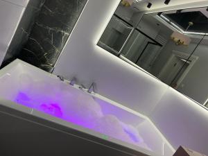 Apartament Primavera 2 z Sauną i Jacuzzi في كيلسي: حمام مع حوض استحمام مملوء بالماء الأرجواني