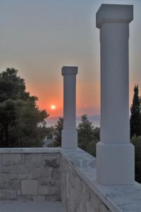 una puesta de sol sobre una pared de piedra con dos columnas en Villa Aries, en Supetar