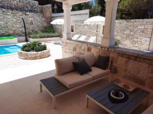 un patio con sofá, mesa y piscina en Villa Aries, en Supetar