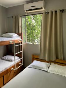 a bedroom with two bunk beds and a window at Lakehouse 24hs Hostel Lagoa Conceicāo in Florianópolis
