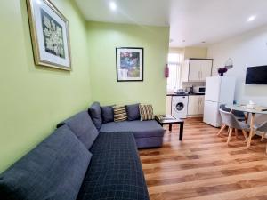 a living room with a blue couch and a kitchen at Comfort Stay Apartments in Birmingham