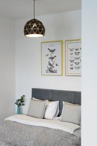 1 cama con sábanas blancas y lámpara colgante en Homewell Apartments Goplana en Poznan