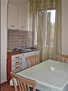 cocina con mesa, fregadero, mesa y sillas en Apartmani Paron Šime, en Seline