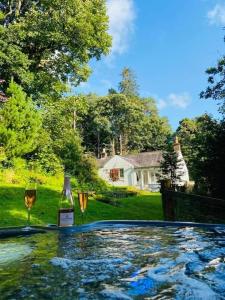 a bottle of wine and two glasses next to a swimming pool at Scaurbridge Cottage with Hot Tub and Sauna in Thornhill