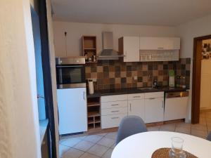 a small kitchen with white appliances and a table at Ferienwohnung Sophie - perfekt mit Kind und Kegel in Eitelborn