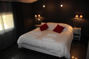 1 dormitorio con 1 cama con sábanas blancas y almohadas rojas en Coeur de Vignes en Saint-Péray
