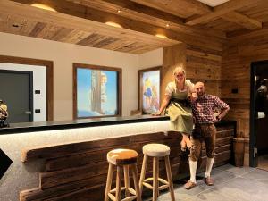 a man and a woman standing at a bar at Albergo Vezzana in Passo Rolle