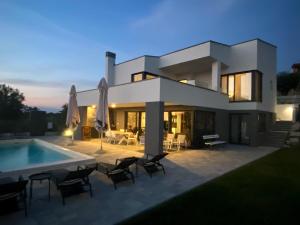 a large white house with a swimming pool at Villa Boiky - private pool and amazing sea view, Istria in Materada