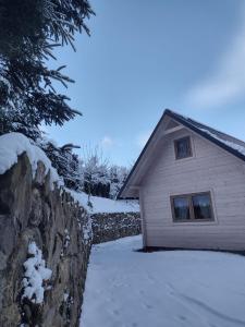 a stone wall next to a house in the snow at Domek Na Leśnym Wzgórzu in Pieszyce
