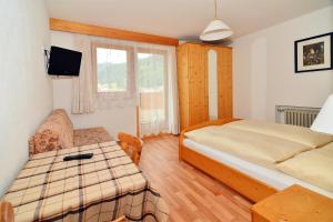 a small bedroom with a bed and a couch at Garni Margherita in Corvara in Badia