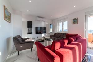 a living room with a red couch and a chair at Apartments Katarina in Kaštela