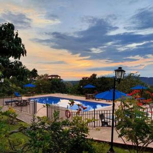 een zwembad met blauwe parasols en een zonsondergang bij Hotel Toscana in La Mesa