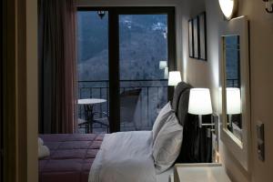 1 dormitorio con 1 cama y balcón con vistas. en Δωμάτια με θέα, en Méga Khoríon