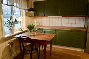 une cuisine avec des placards verts et une table et des chaises en bois dans l'établissement Vadstena innerstad, à Vadstena