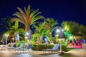 a group of chairs and palm trees at night at Athos Hotel in Nydri