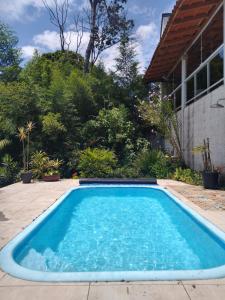 a large blue swimming pool in front of a house at Recanto das Orquídeas Domingos Martins- Soido De Cima,4km centro in Domingos Martins