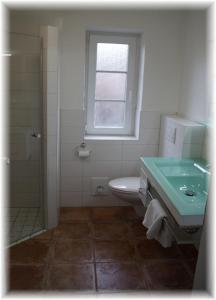 łazienka z umywalką, toaletą i oknem w obiekcie Haus Wattenblick EG w mieście Morsum