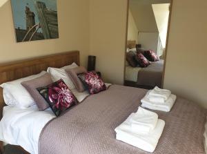 a bedroom with a bed with towels and a mirror at The Eaves in Lynton, Exmoor, Devon in Lynton