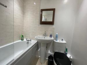 a bathroom with a sink and a toilet and a bath tub at Modern 1 Bed ground floor apartment in Dartford