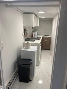 a small kitchen with white appliances and a trash can at Nice Studio Livry in Livry-Gargan +8 photos
