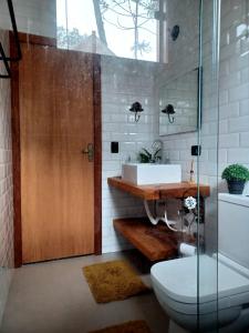 a bathroom with a toilet and a sink and a wooden door at Sopro da Serra Chalés in Gonçalves