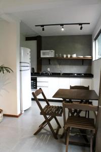a kitchen with a table and chairs and a refrigerator at Pousada Refúgio do Vale - Praia do Rosa in Praia do Rosa
