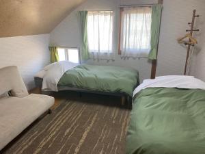 a bedroom with two beds and a couch in it at Guesthouse Akane-yado in Nakafurano