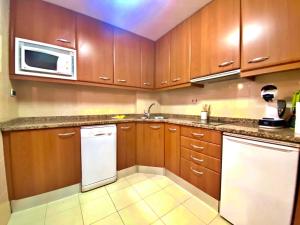 a kitchen with wooden cabinets and a sink and a microwave at Tucamp 2,2 Justo al lado del telecabina in Encamp