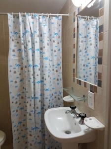 Un baño con lavabo y cortina de ducha. en Hosteria Torino, en Valeria del Mar 52 fotos más