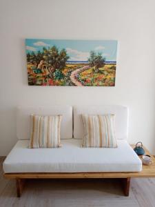 un dipinto appeso sopra un divano bianco con cuscini di Scialè Salento Casa Vacanza a Lido Conchiglia
