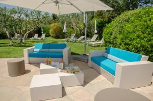 un patio con muebles azules y blancos y una sombrilla en Mas de l'Oulivié, en Les Baux-de-Provence