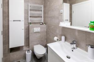 a bathroom with a white toilet and a sink at MB Apartment 2 in Subotica +25 photos