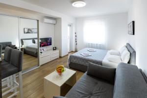 a living room with a couch and a bed and a mirror at MB Apartment 2 in Subotica