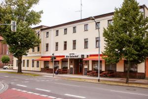 a white building on a street with tables and chairs at Hotel am Bahnhof in Stendal