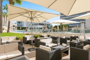 a patio with chairs and umbrellas and a pool at Trendhotel Alcudia - Adults Only in Port d'Alcudia