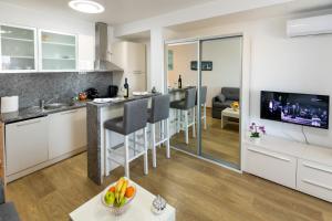 eine Küche und ein Wohnzimmer mit weißen Schränken und einem TV in der Unterkunft MB Apartment 2 in Subotica