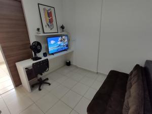 ein Wohnzimmer mit einem TV und einem Sofa in der Unterkunft Aconchego Encantador in Viçosa