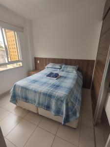 a bedroom with a bed with a blue comforter at Aconchego Encantador in Viçosa
