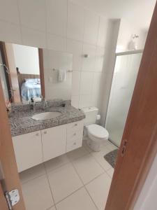 a white bathroom with a sink and a toilet at Aconchego Encantador in Viçosa